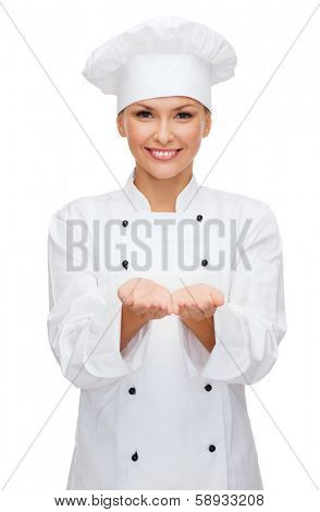 cooking, advertisement and food concept - smiling female chef, cook or baker holding something on palm of hands