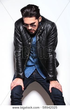 fashion man resting and looking down, against studio wall