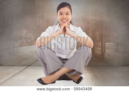 Businesswoman sitting cross legged with hands together against urban projection on wall