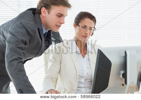 Smartly dressed business couple using computer at office desk
