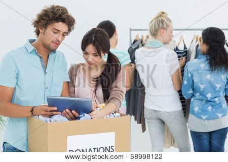 Group of young people with clothes donation while using digital tablet