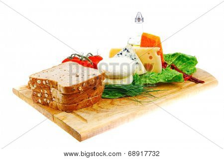 fresh aged french cheeses chops on big cutting board with tomatoes olive oil, rye breadm and green chives isolated over white background