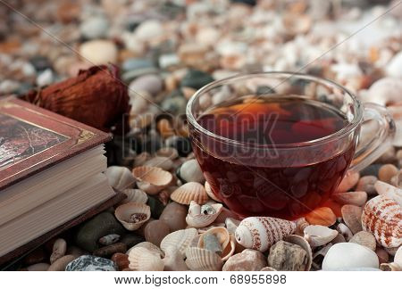 book and transparent glass cup with tea standings on shells