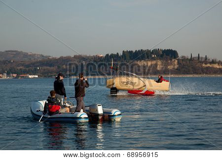Portoroz, Slovenia - 6 May, 2014: Men riding a motorised vessel on foils in the sea and other men watching him on a boat.