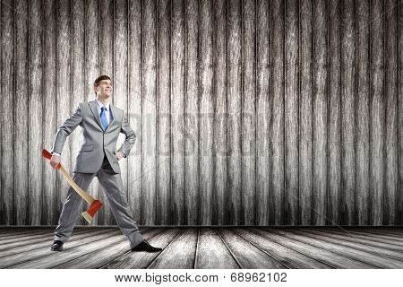 Young determined businessman in suit holding big axe