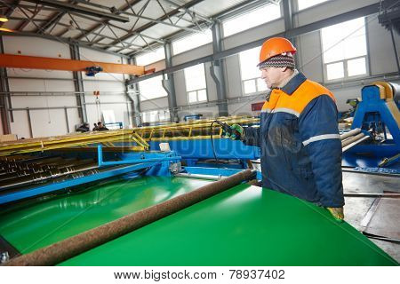 industrial worker operating metal sheet profiling mechine at manufacturing factory