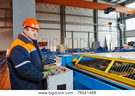 industrial worker operating metal sheet profiling mechine at manufacturing factory