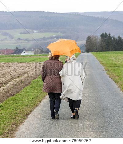 Women In Rain Under An Umbrella In Rural Landscape