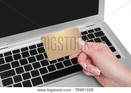 Woman Holding Gold Credit Card In Hand. On-line Shopping On The Internet Using A Laptop.