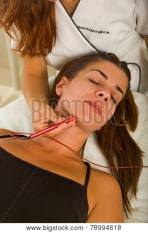 Attractive female patient receiving electro acupuncture on face as part of a anti-aging beauty treatment