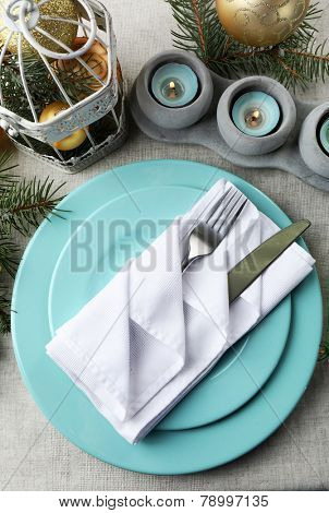 Christmas table setting in blue, golden and whitec olors on grey tablecloth background