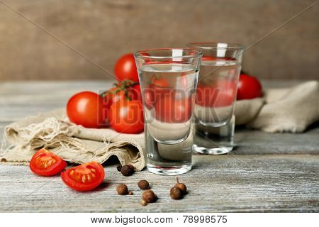 Glasses of ouzo and tomatoes on wooden table
