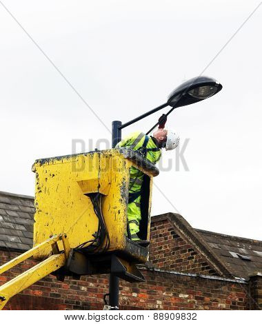 Worker paints a street lamp