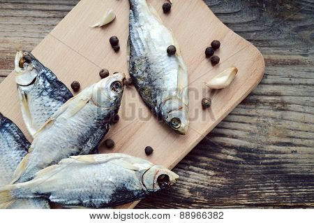 Salty stockfish cod on wooden board with gaarlic and pepper