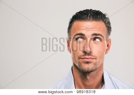 Closeup portrait of a handsome man looking away at copyspace over gray background