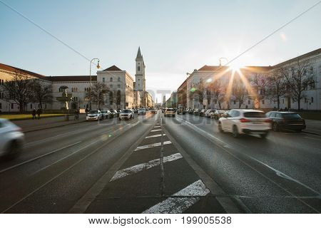 View of the road on the street Leopoldstrasse in Munich, Germany. Fast blurred motion car on sunset background.