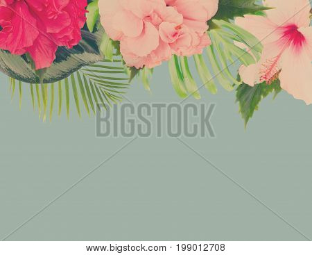 tropical fresh flowers and leaves - border of fresh multicilored hibiscus flowers and exotic palm leaves on blue, retro toned