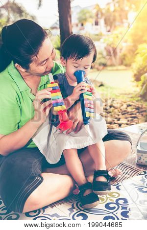 Asian Mother Playing Plastic Trumpet Pipe With Her Daughter. Vintage Tone.