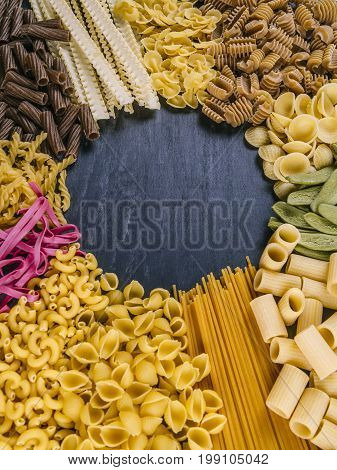 Photo of twelve different pasta types arranged on a slate surface as a frame.