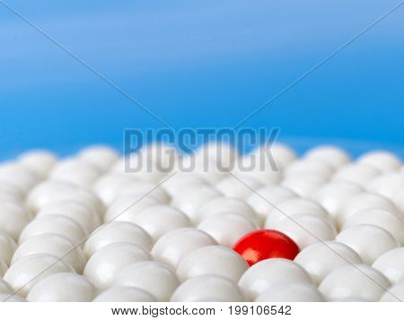 stand out red ball surrounded by white balls on blue background. selective focus