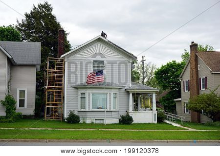 CADILLAC, MICHIGAN / UNITED STATES - MAY 31, 2017: A home, in Cadillac's Courthouse Hill Historic District, flies the American flag, while undergoing restoration.