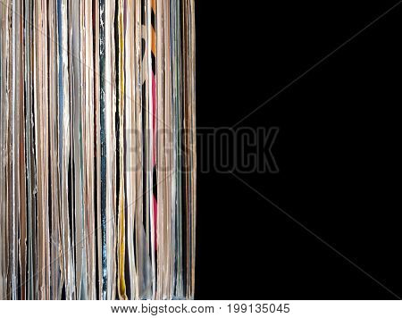 Pile of many close standing vinyl records in old color covers on left side on photo over black background studio shot front view closeup