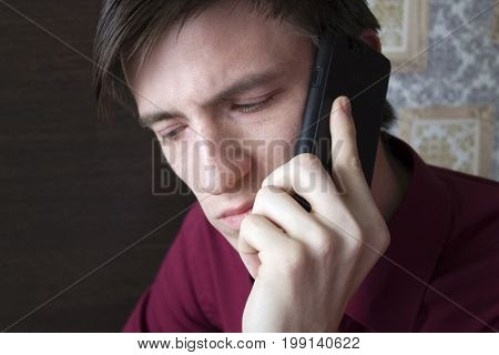 Young guy talking on the phone looking down
