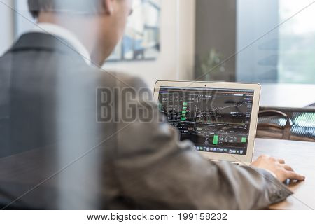 Corporate businessman analyzing economic data on laptop computer. Man's hands on notebook computer, business person at workplace.
