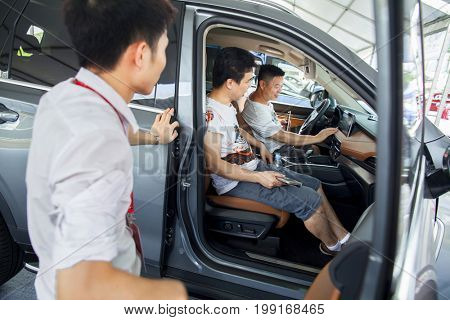 Dongguan, Guangdong, China - August 7, 2017: Car salesperson talking with prospective Chinese brand automobile buyers at Dongguan car exhibition