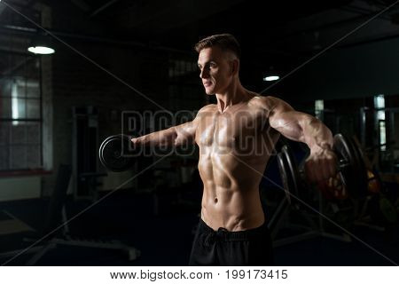 sport, bodybuilding, fitness and people concept - close up of young man with dumbbells flexing muscles in gym