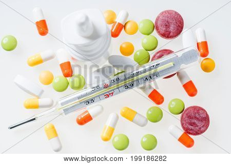 Thermometer pills nasal spray on white background. Cold and flu concept - Top View