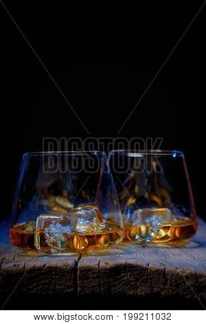 Glass of scotch whiskey and ice isolated on wooden table