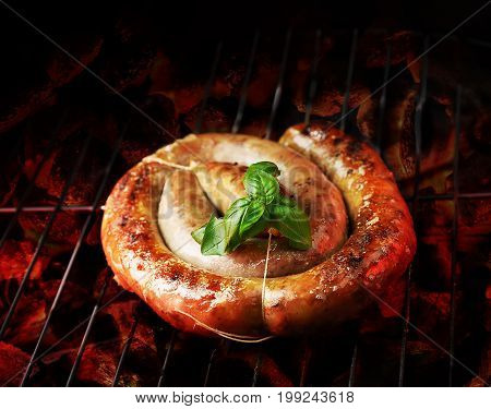 cumberland sausage, spiral pork sausage on bbq grill with flame, homemade