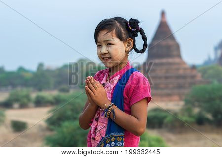 Burmese girl with traditional thanaka on her face praying on pagoda blurred background at bagan in Mandalay Myanmar