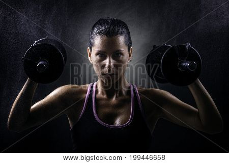 Sport young woman with dumbells on dark background