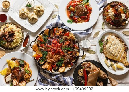 Presentation of variety georgian cuisine in restaurant. Stewed mutton and vegetables, grilled fish, khinkali, shawarma and other meat dishes with souce