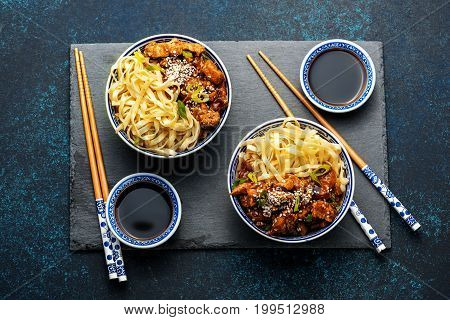 Chicken teriyaki on dark background with balsamic sauce and sesame seeds. Asian food. Noodles, chicken and soy sauce. Top view.