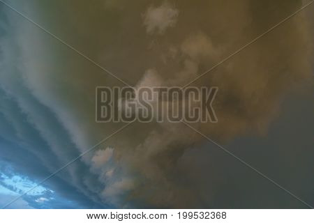 Impending storm with dark clouds on clear blue sky. Illustration of danger.