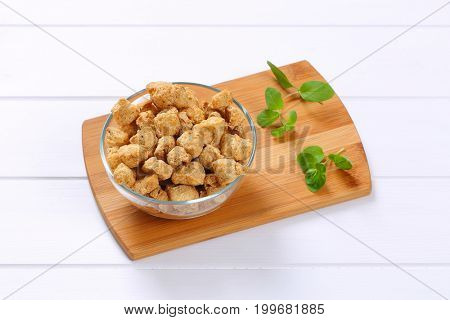 bowl of soy meat cubes on wooden cutting board