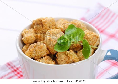mug of soy meat cubes on checkered dishtowel - close up