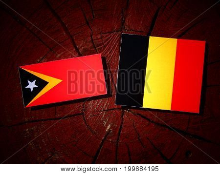 East Timorese Flag With Belgian Flag On A Tree Stump Isolated