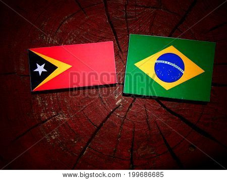 East Timorese Flag With Brazilian Flag On A Tree Stump Isolated