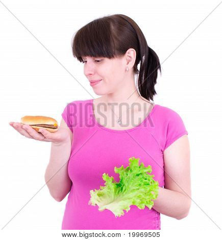 Mladá žena vybere mezi hamburger a salátem
