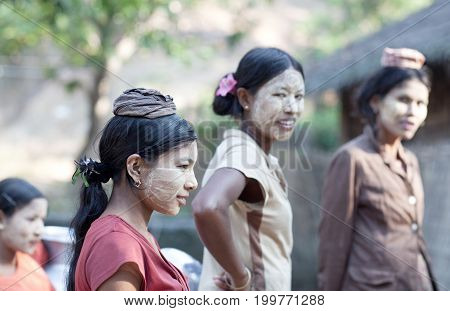 MYITKYINA, MYANMAR - JANUARY 4, 2012: Burmese girls with thanaka paste on their faces going to local market. Thanaka is a yellow cosmetic paste made from ground bark.