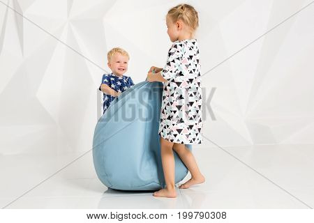 Brother and sister playing and smiling in a white studio. Little children on studio shot