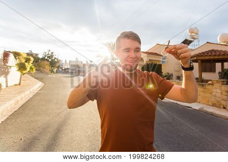 Happy young man showing off the key to his new home. Owner, real estate and people concept.