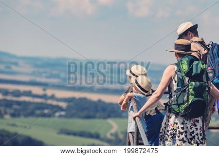 Happy family is on a trip looking out of the landscape. Concept of a happy sports family. Family with hats on the head.