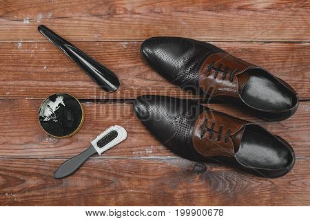 Shoe care. Shoe wax and brushes on wooden surface.