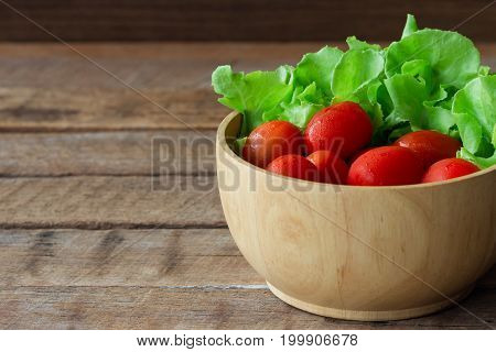 Fresh Tomato And Lettuce In Wood Bowl Put On Wood Table. Side View Close Up Of Tomato And Green Oak