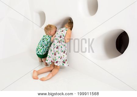 Brother and sister playing and smiling in a white studio. Little children on studio shot